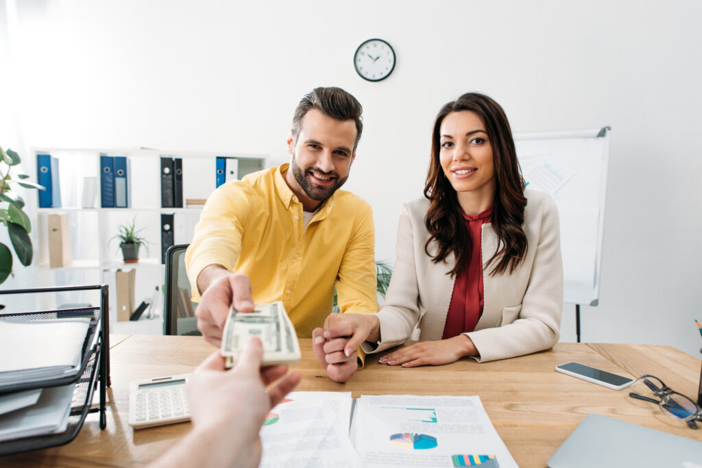Photo of couple handing over payment to low-interest creditor. At the end of FOO, step 9 dictates paying off your remaining low-interest debt.